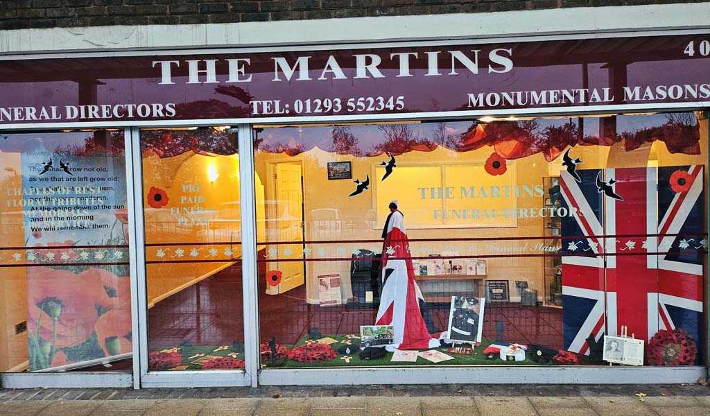 The Martins Remembrance Day window display. There are union jack flags, poppy wreaths and photos of soldiers in the window.